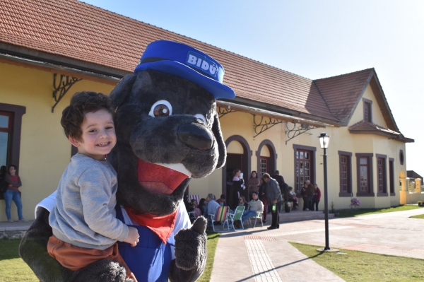 Cão Bilú, o mascote do município, concebido em parceria com projeto de extensão ligado ao Geoparque. Ao fundo, Estação Férrea (Foto: Comunicação/ Prefeitura de Restinga Sêca).